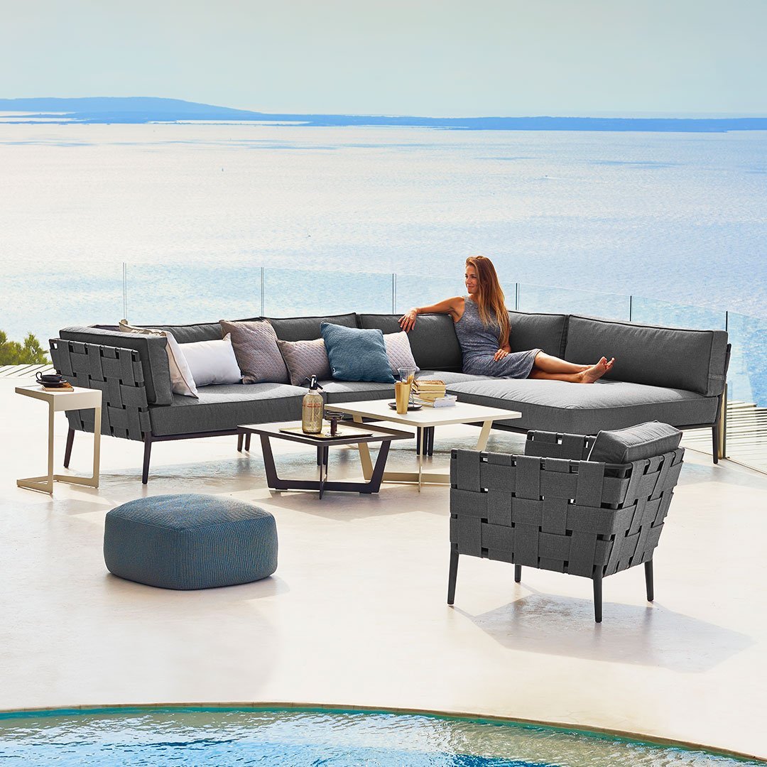Modern outdoor sectional sofa in sleek gray with plush white and blue cushions, featuring a trendy geometric pattern.