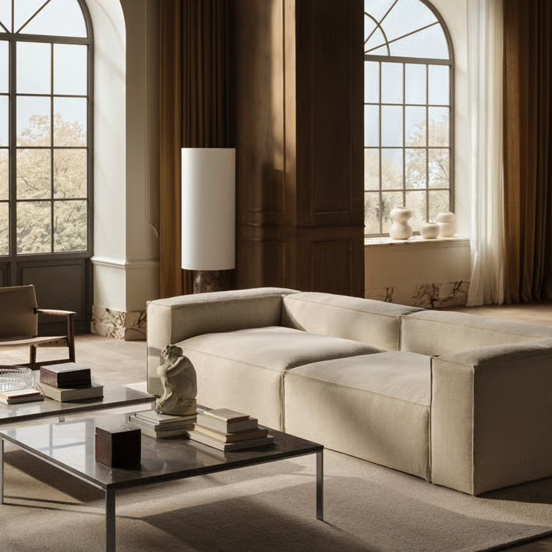 Beige modern sectional sofa with clean lines, paired with a glass coffee table in a neutral-toned living room.
