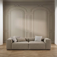 Neutral beige sofa with clean lines, paired with soft light-colored cushions against a minimalist backdrop.