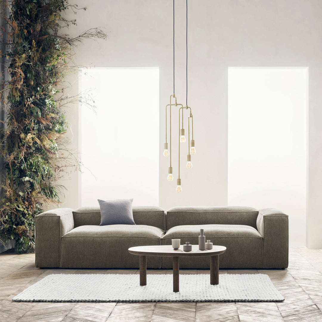 Modern gray sofa with a textured pattern, paired with a light rug and earthy tones from plants and wooden accents.
