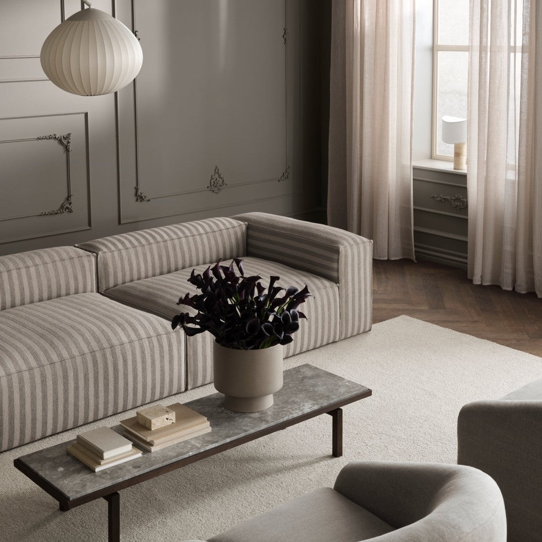 Striped gray and beige sofa in a stylish living room setting, paired with textured curtains and a minimalist coffee table.