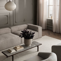 Striped gray and beige sofa in a stylish living room setting, paired with textured curtains and a minimalist coffee table.