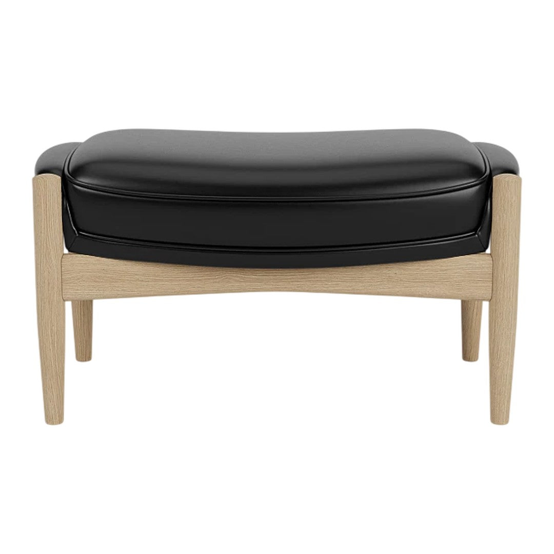 Black leather ottoman with light wooden legs, featuring a smooth, curved design. Perfect for modern interiors.