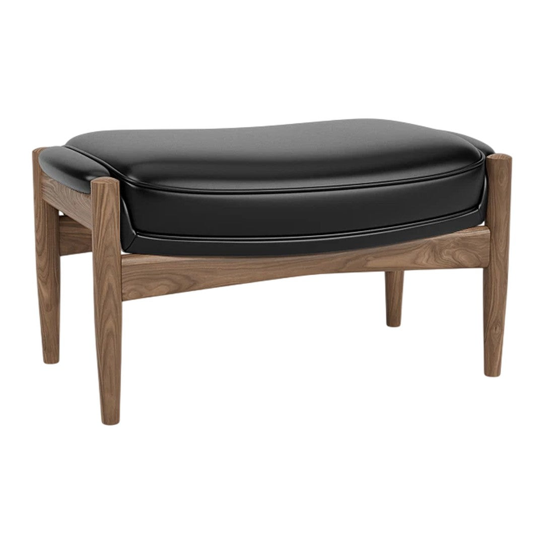 Black leather ottoman with a smooth, contoured design and natural wood legs in a warm walnut finish.