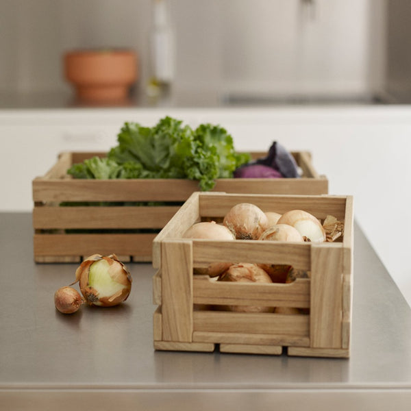Natural wooden crates in light beige, featuring slatted designs, holding fresh vegetables with vibrant greens and purples.
