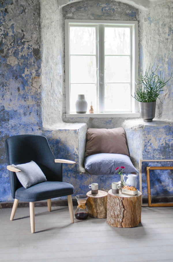 Cozy seating area with blue textured walls, natural wood accents, and soft gray and white cushions.