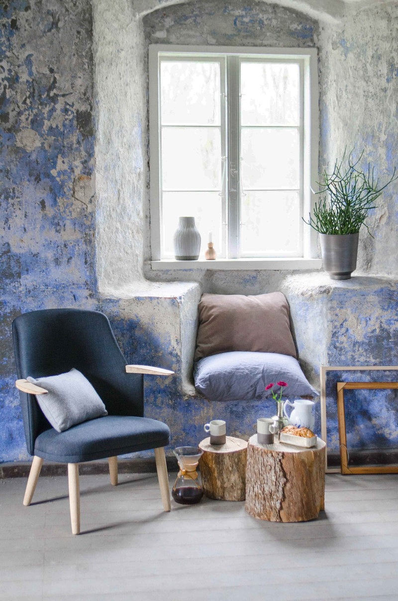 Cozy seating area with blue textured walls, natural wood accents, and soft gray and white cushions.