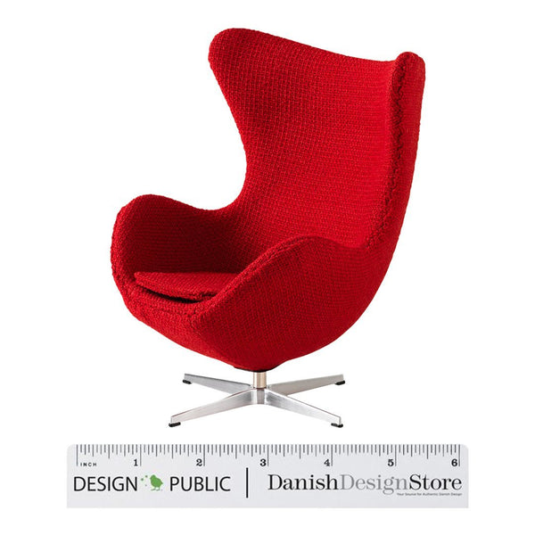 Modern red upholstered chair with a unique curved shape and textured fabric pattern, featuring a sleek metal base.