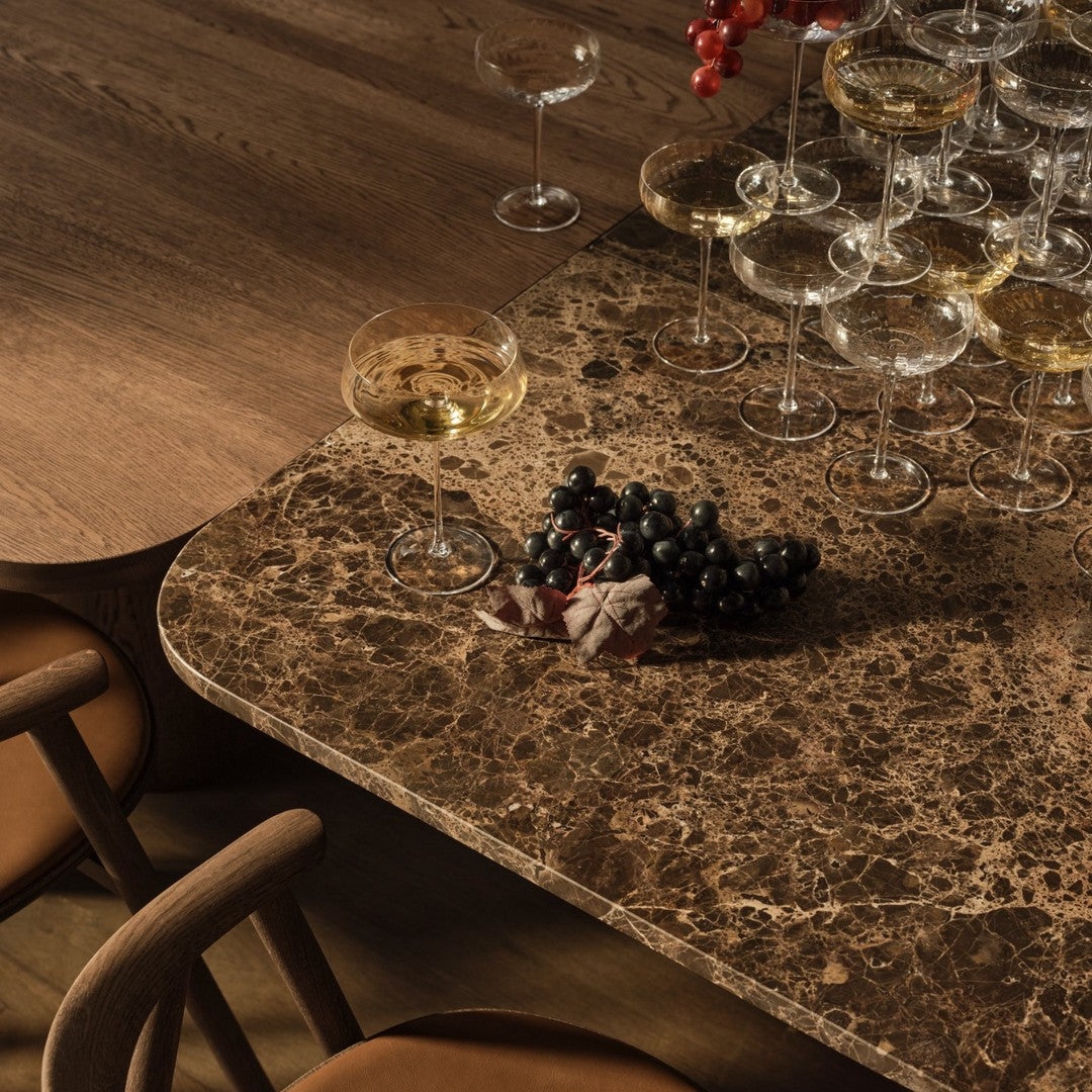Elegant brown marble tabletop with intricate patterns, complemented by gold glasses and dark grapes.