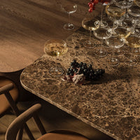 Elegant brown marble tabletop with intricate patterns, complemented by gold glasses and dark grapes.