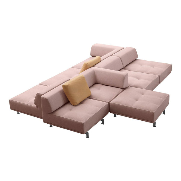 Modern sectional sofa in soft blush pink upholstery with tufted design and a contrasting mustard yellow accent pillow.