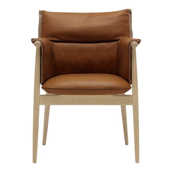 Brown leather chair with a sleek design and light wooden legs, featuring a textured pattern and comfortable cushions.