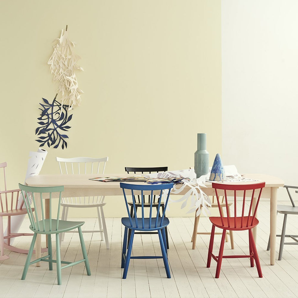 Colorful chairs in pastel shades, including pink, green, blue, red, and black, set against a soft yellow background.