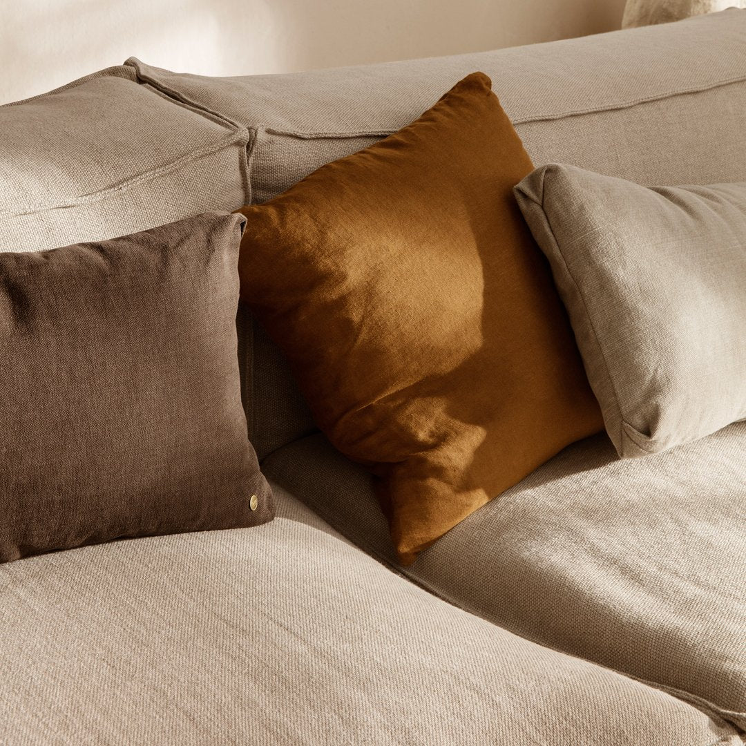 "Plush linen pillows in warm brown and mustard yellow on a soft beige sofa, featuring subtle textures."