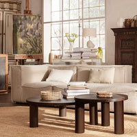 Set of two round wooden coffee tables in dark brown, paired with a neutral beige sofa and textured natural rug.
