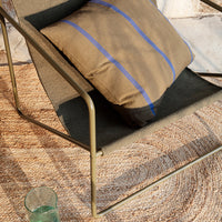 Brown and blue striped cushion on a modern chair with a textured gray fabric, set against a natural woven rug.