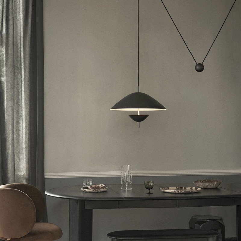 Modern pendant lamp in matte black with white accent, surrounded by neutral gray and soft earth tones.