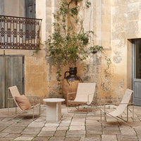 Neutral-toned patio chairs with beige cushions, surrounded by textured stone flooring and rustic, warm-hued walls.