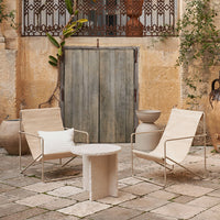 Neutral beige chairs and a textured cream side table against a rustic stone courtyard backdrop.
