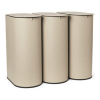 "Set of three cylindrical storage bins in a soft beige tone with sleek, minimalist design and dark base accents."