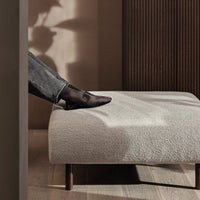 Elevated beige ottoman with a soft texture, featuring dark wood legs and a minimalistic design. Balanced with warm tones.