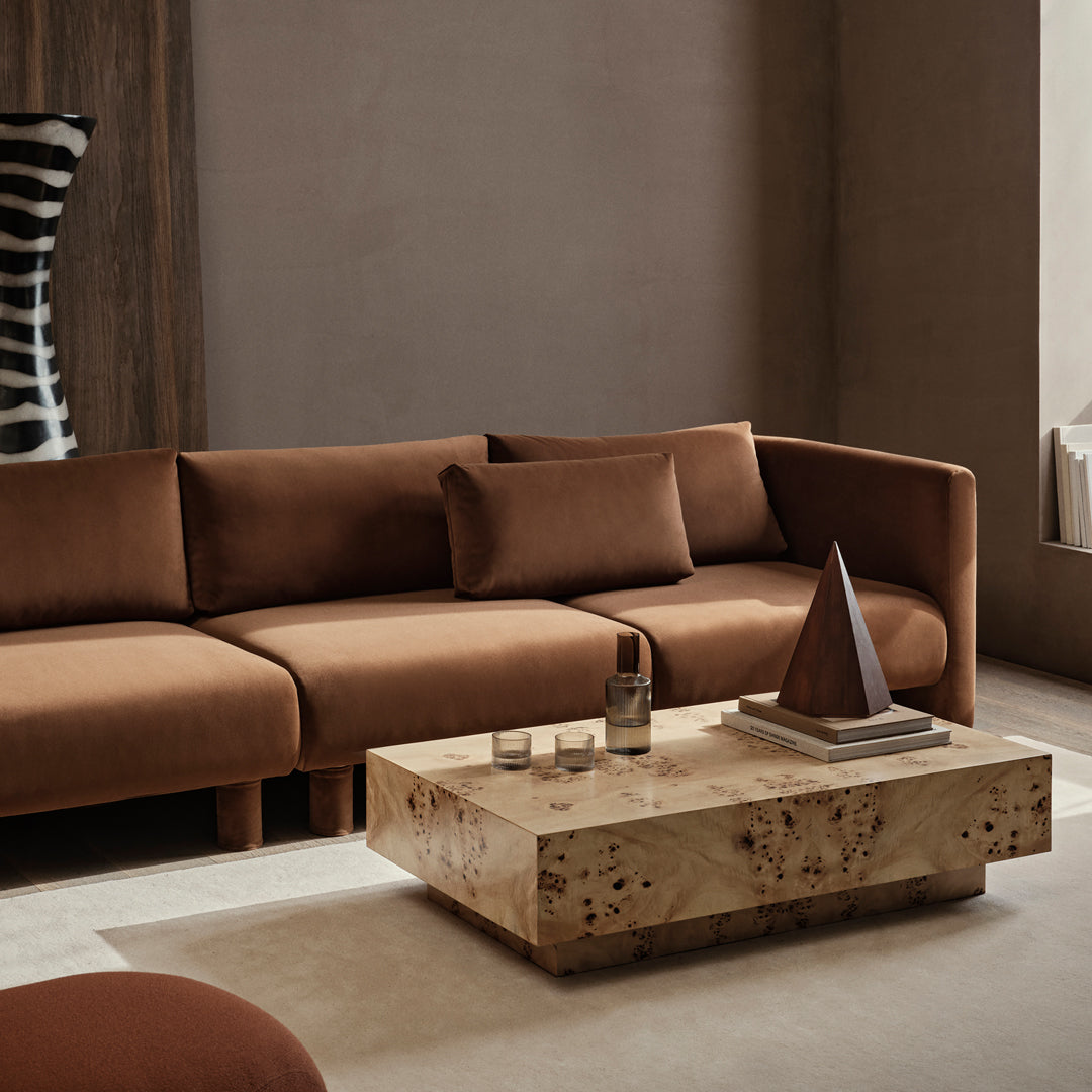 Brown velvet sofa with minimalist design, paired with a natural wood coffee table and geometric decor.