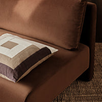 Brown sofa with a geometric patterned cushion featuring shades of beige, taupe, and dark brown.