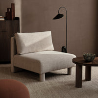 Light beige upholstered chair with textured fabric, accented by a minimalist black lamp and warm neutral tones.