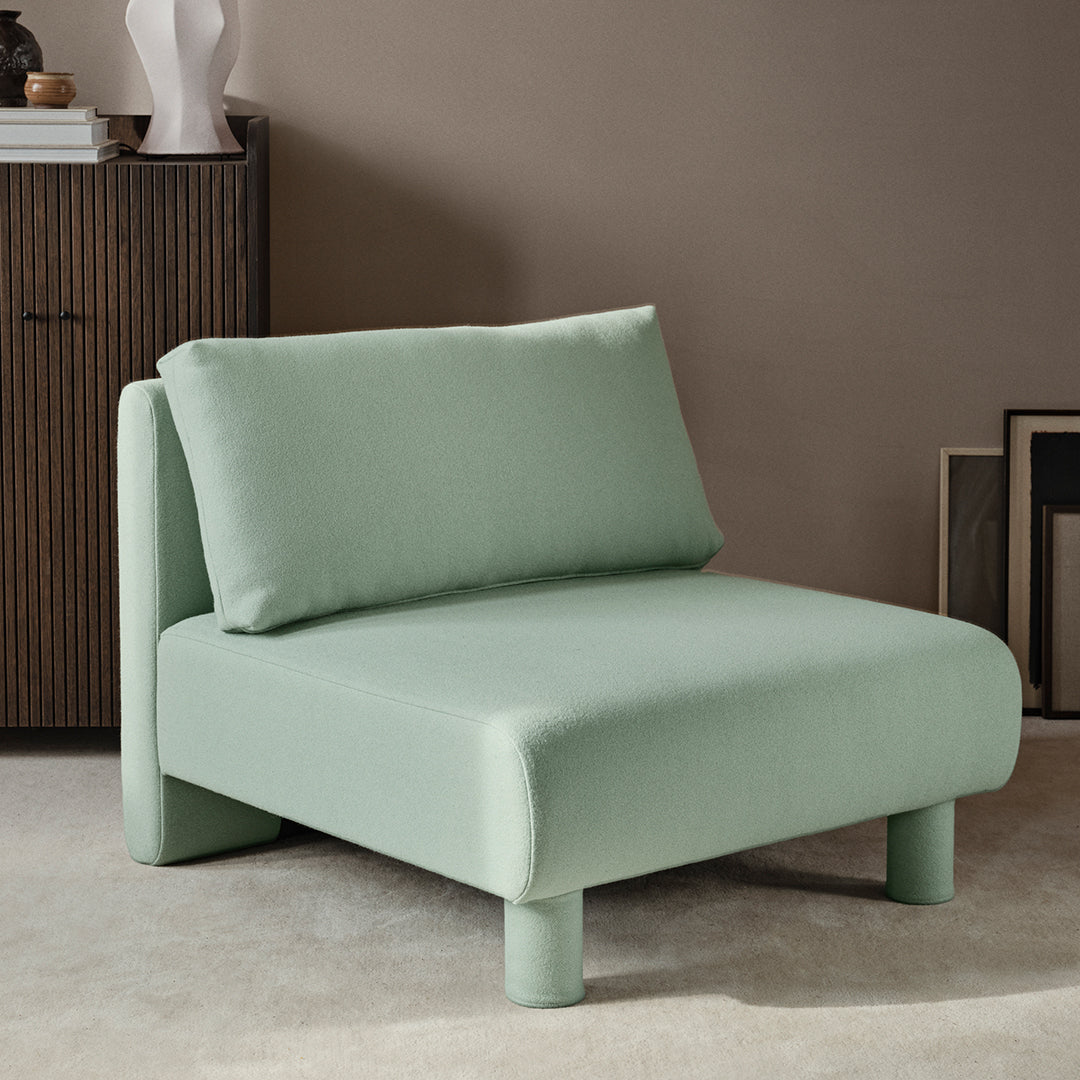 Mint green upholstered chair with a minimalist design and soft, smooth texture, featuring a matching cushion.