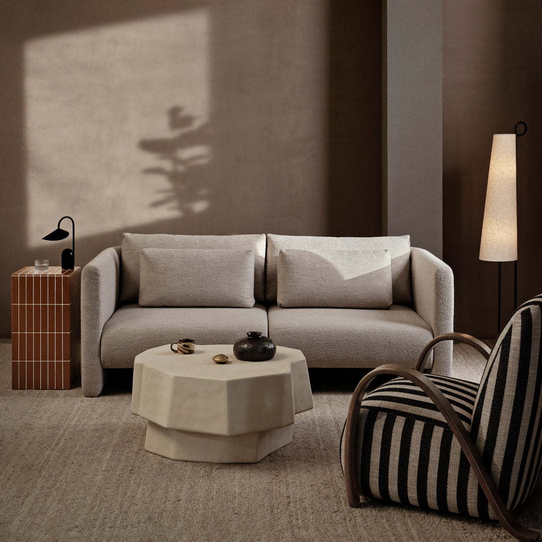 Neutral-toned modern sofa with soft textures, paired with a geometric coffee table and striped armchair.