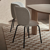 Gray upholstered dining chairs with black legs, positioned on a beige and cream patterned rug.