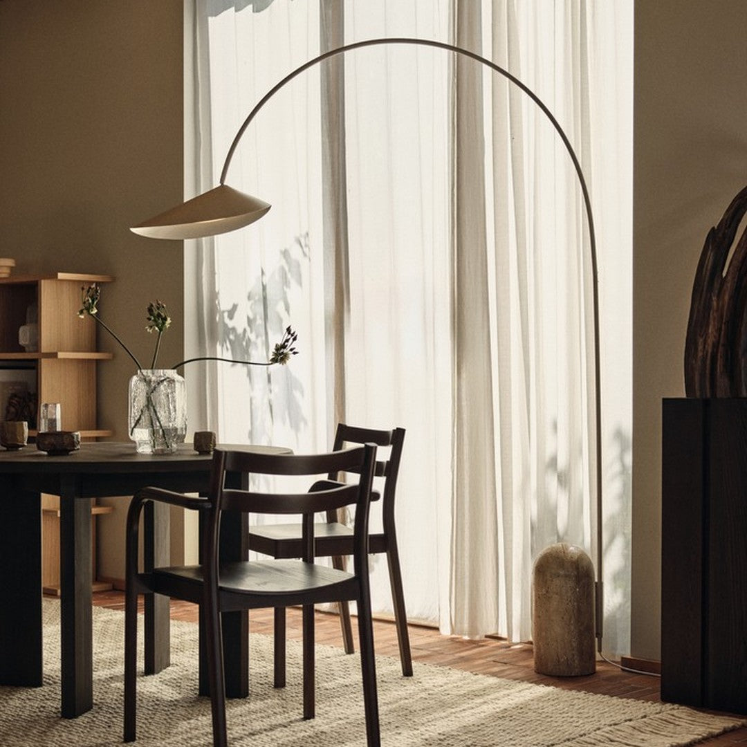 "Elegant arc floor lamp with a soft beige shade, complemented by dark wood furniture and neutral-toned textiles."