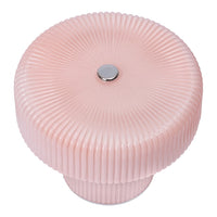Round pink lamp with ribbed texture and a silver button accent. Elegant design adds a soft touch to any decor.