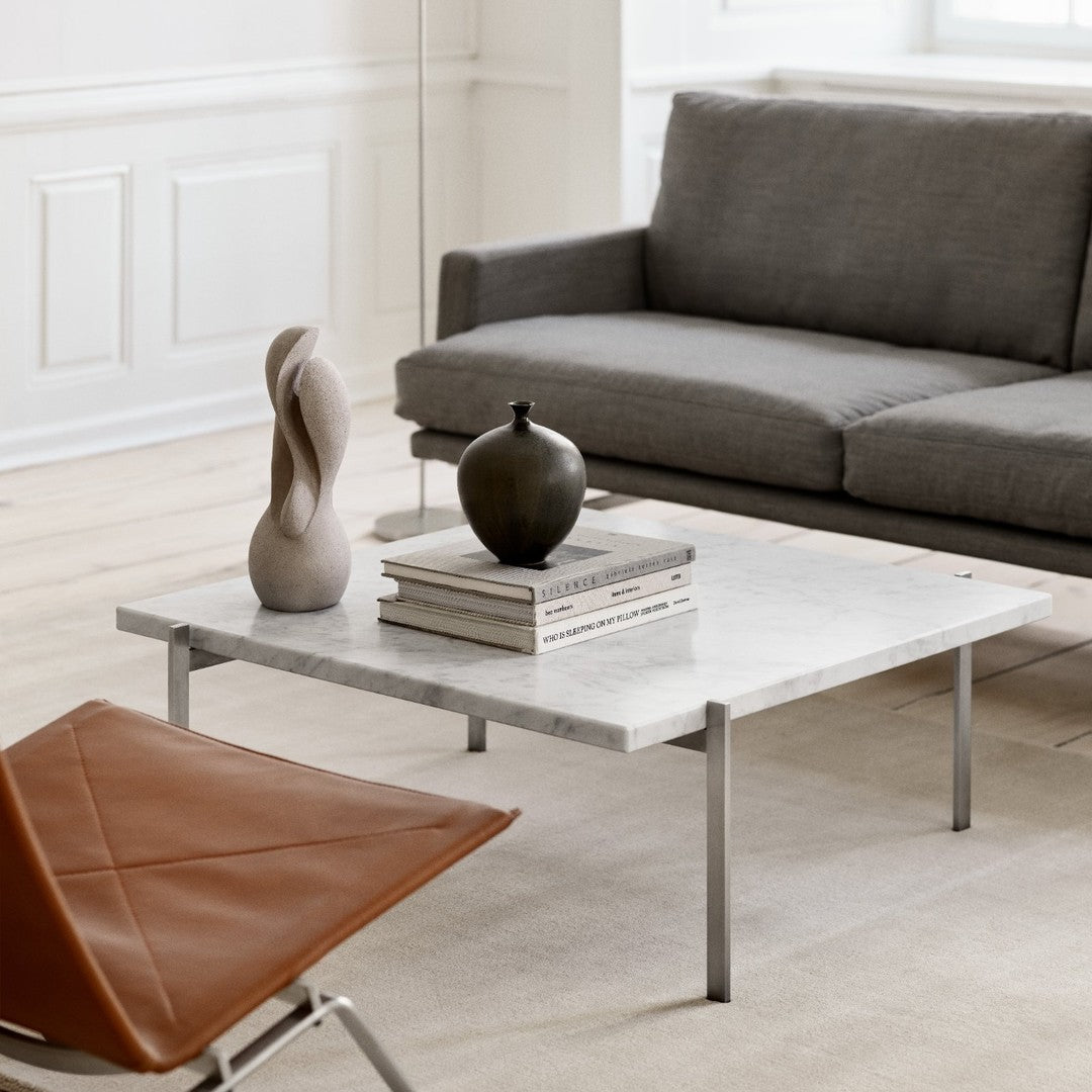 Modern gray sofa, white marble table, brown leather chair, decorative black and beige accents for a chic living room.