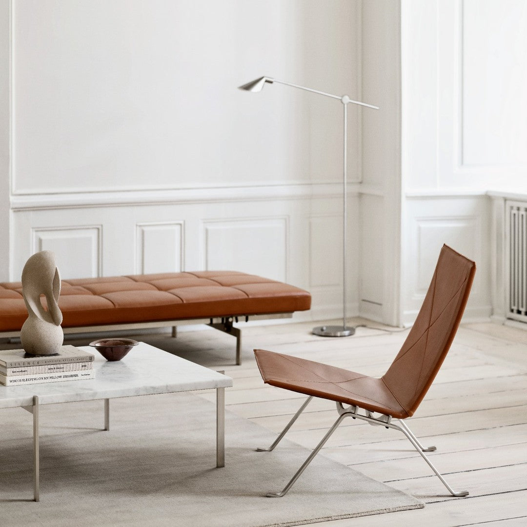 Stylish brown leather chair with minimalist silver accents, set against a neutral-toned, modern interior.
