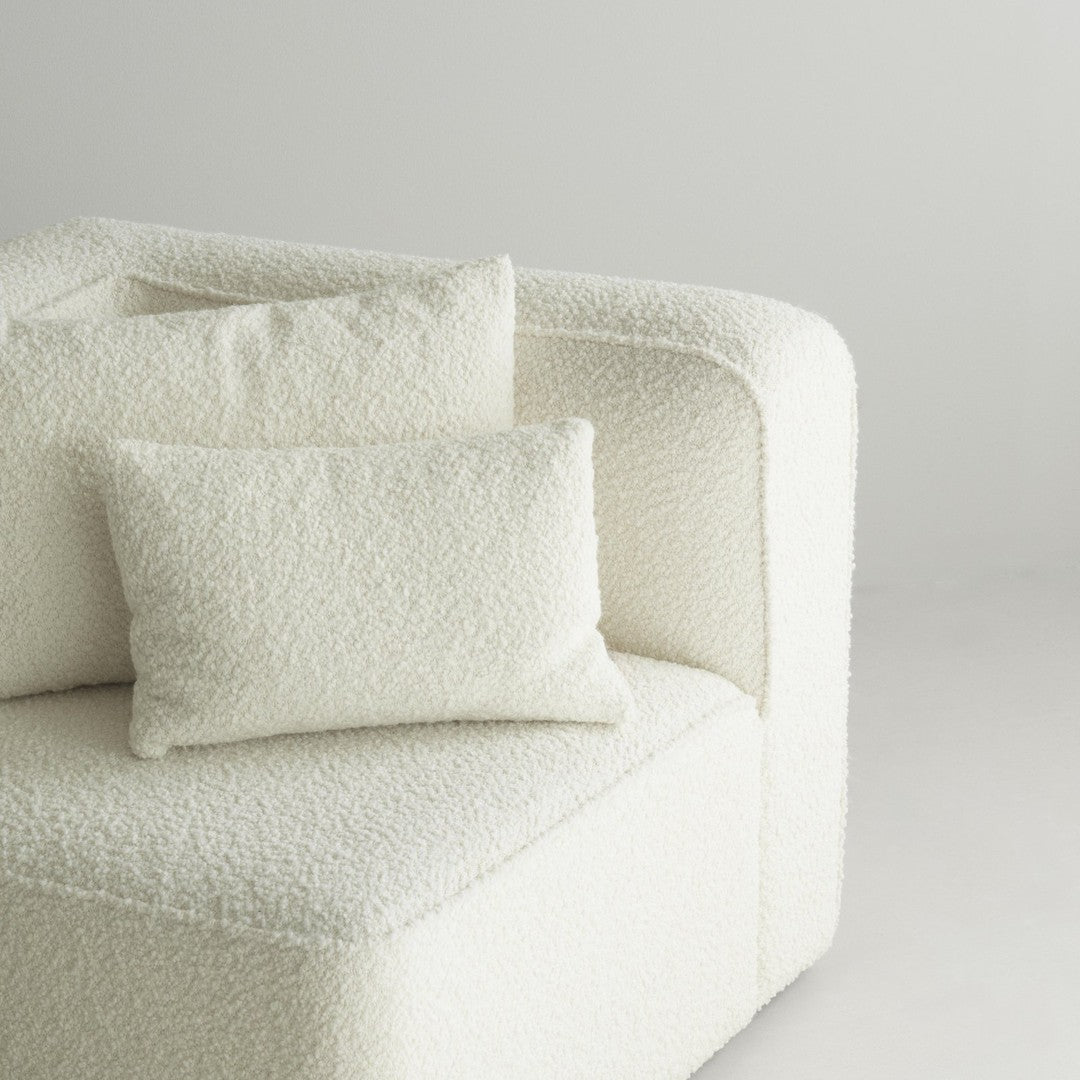 Textured white upholstery with plush pillows, featuring a cozy, neutral tone for modern elegance.