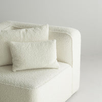 Textured white upholstery with plush pillows, featuring a cozy, neutral tone for modern elegance.