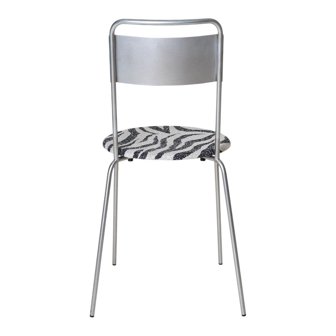 Silver metal chair with a black and white zebra print seat. Modern design with sleek lines and bold patterns.
