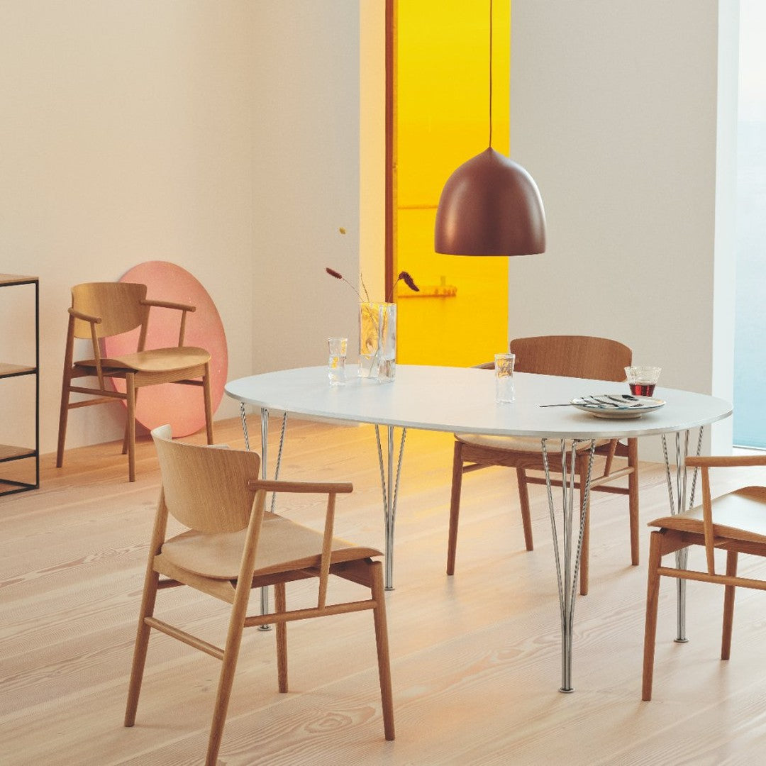 Modern dining scene featuring a white oval table, warm wood tones, and a copper pendant light against soft pastel accents.