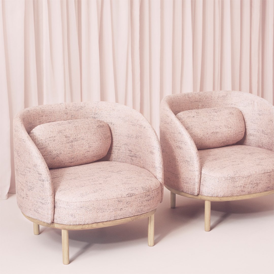 Soft pink armchairs with subtle textured pattern and gold legs, against a pastel curtain backdrop.