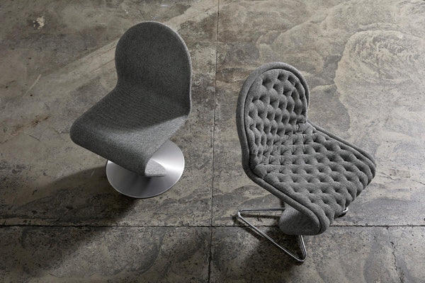 Two modern chairs in textured grey upholstery with a clean design on a concrete floor.