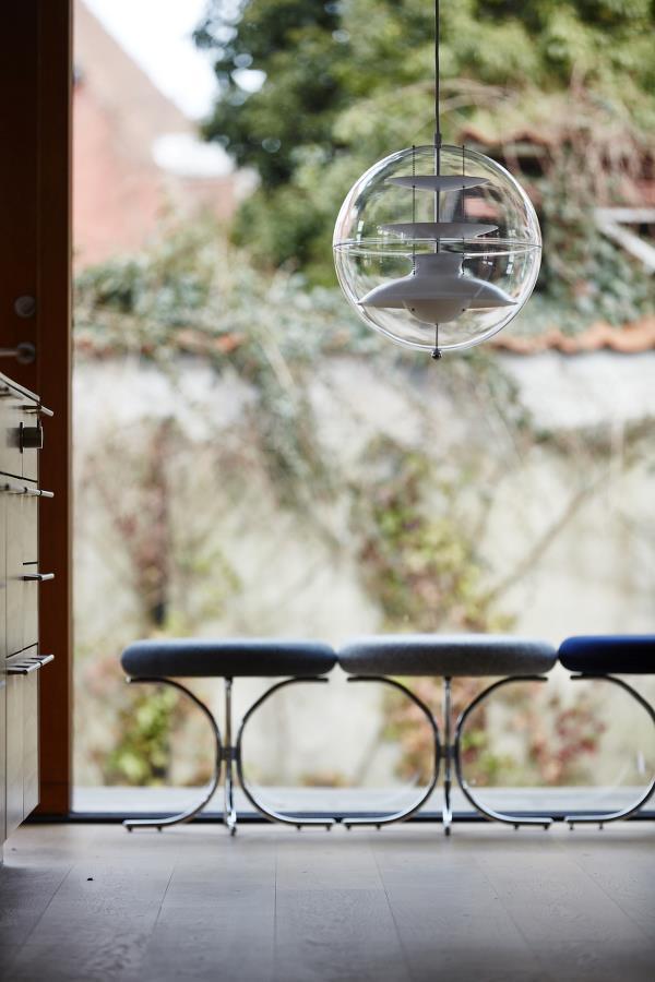 Modern chrome chair with blue cushion in a bright, airy space, complemented by a clear globe pendant light.