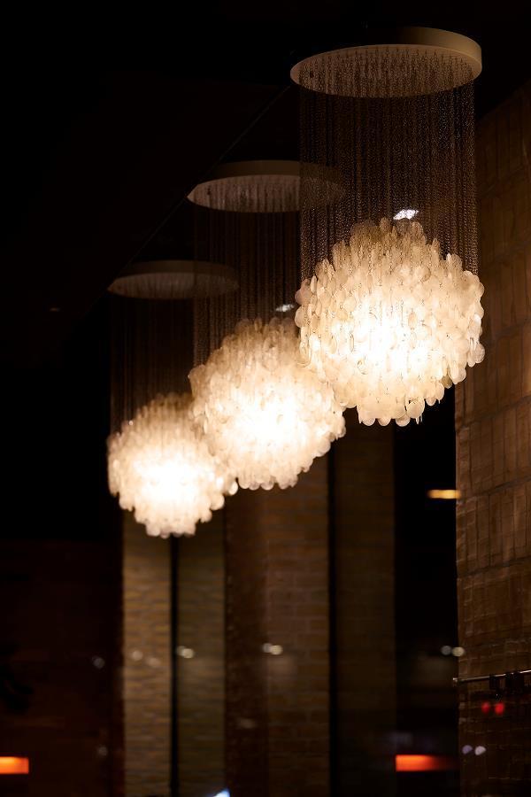 Three elegant, white, cloud-shaped pendant lights hanging from dark ceilings, casting soft illumination.