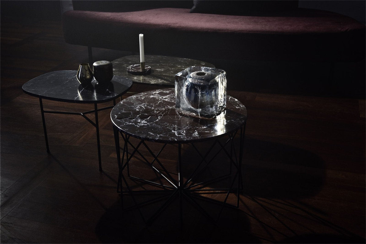 "Set of three modern coffee tables with dark marble tops and black metal legs, featuring unique veining patterns."