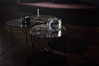 "Set of three modern coffee tables with dark marble tops and black metal legs, featuring unique veining patterns."