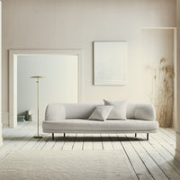 Light gray sofa with a smooth texture, complemented by soft white accents in a minimalistic, neutral-toned room.