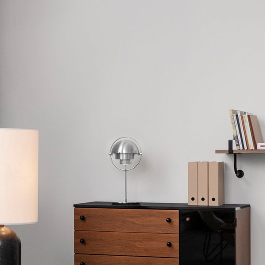 Modern wooden dresser with black accents, silver lamp, and neutral walls; minimalist design enhances soft colors.