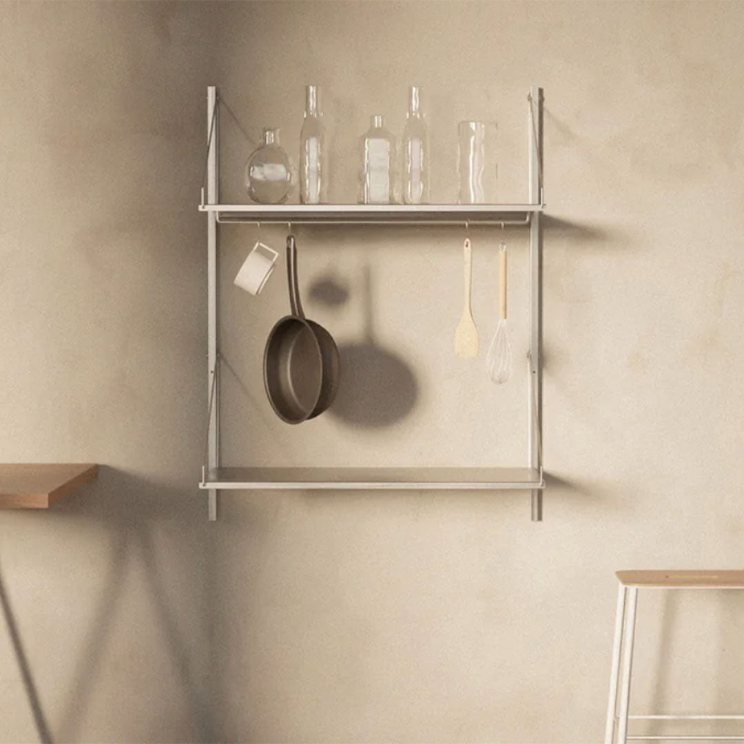 "Sleek silver shelf with glass bottles and wooden utensils against a neutral beige wall, showcasing minimalist design."