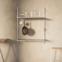 "Sleek silver shelf with glass bottles and wooden utensils against a neutral beige wall, showcasing minimalist design."