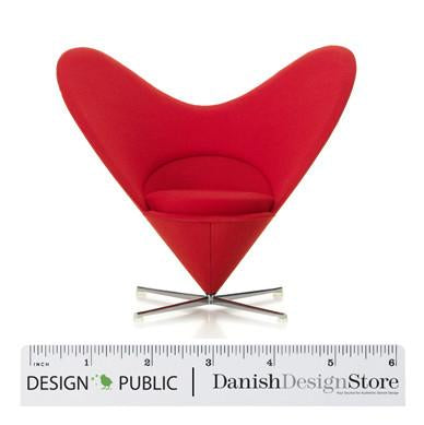 Bright red heart-shaped chair with smooth fabric surface and sleek chrome base. Ideal for modern decor.